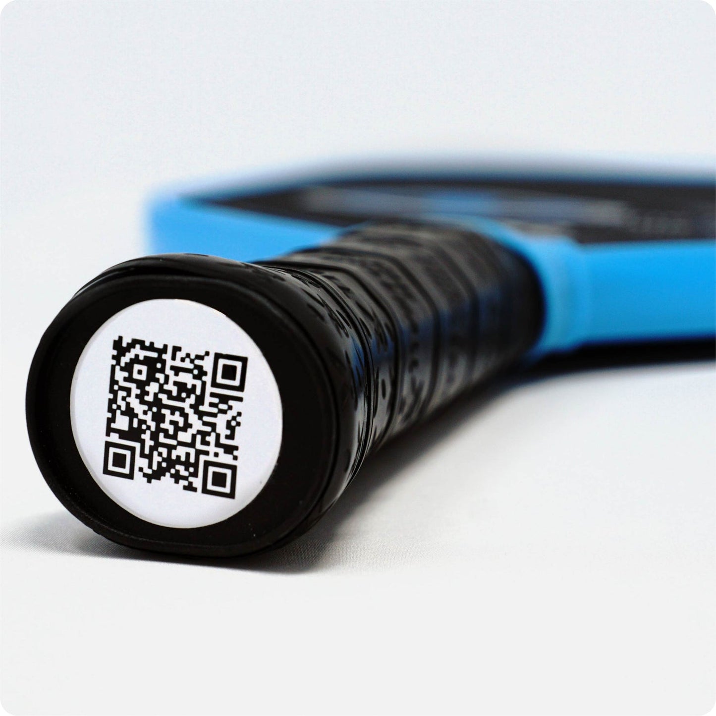 Close-up of pickleball paddle grip with QR code, showcasing authentication and a included cover.