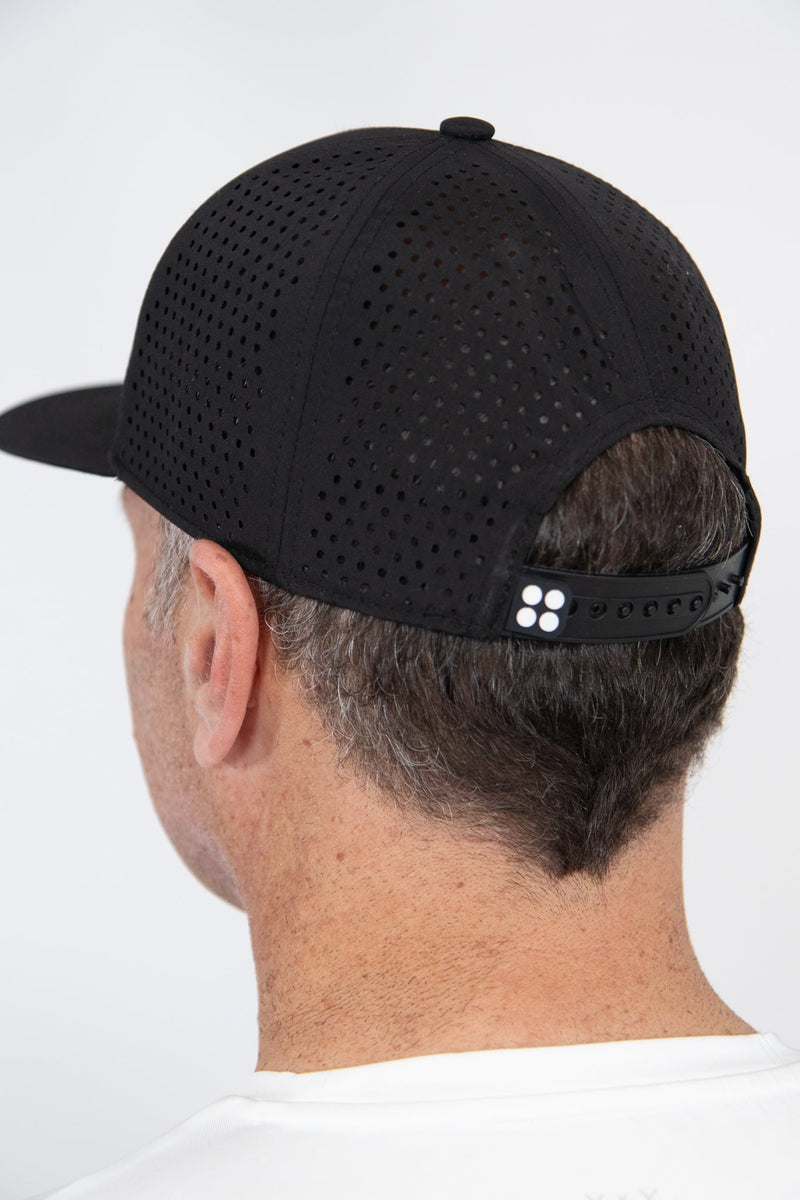 Black perforated snapback hat with adjustable strap, shown from the back on a man's head.