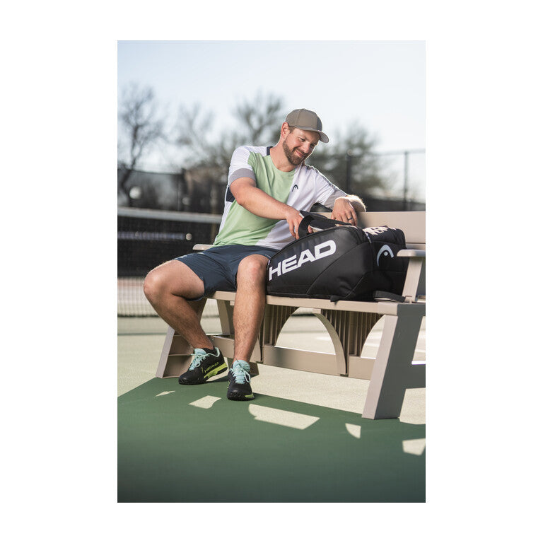 Man with pickleball bag on outdoor court bench
