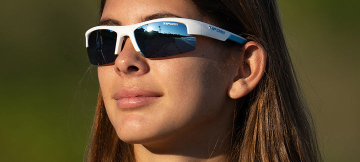 Woman wearing white and blue sunglasses outdoors.