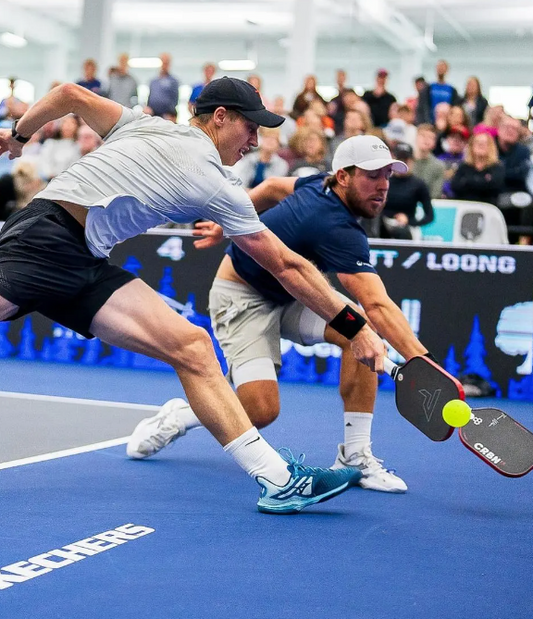 Pickleball players in action on an indoor court.