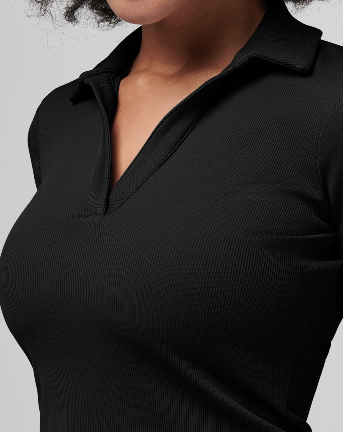 Close-up of ribbed, black knit polo shirt with V-neck collar.
