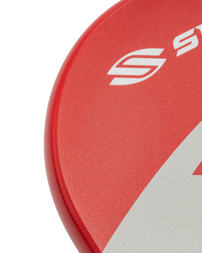 Close-up of a red pickleball paddle with a textured surface and white logo detail.
