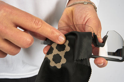 Close-up of hands cleaning clear pickleball eyewear with a microfiber cleaning cloth.
