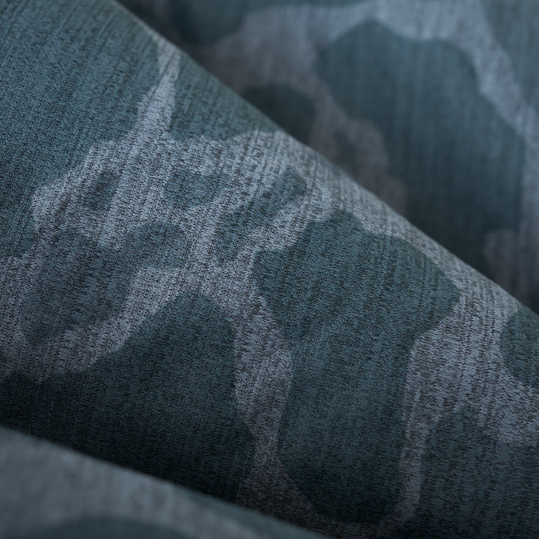 Close-up of textured teal long-sleeve shirt fabric.
