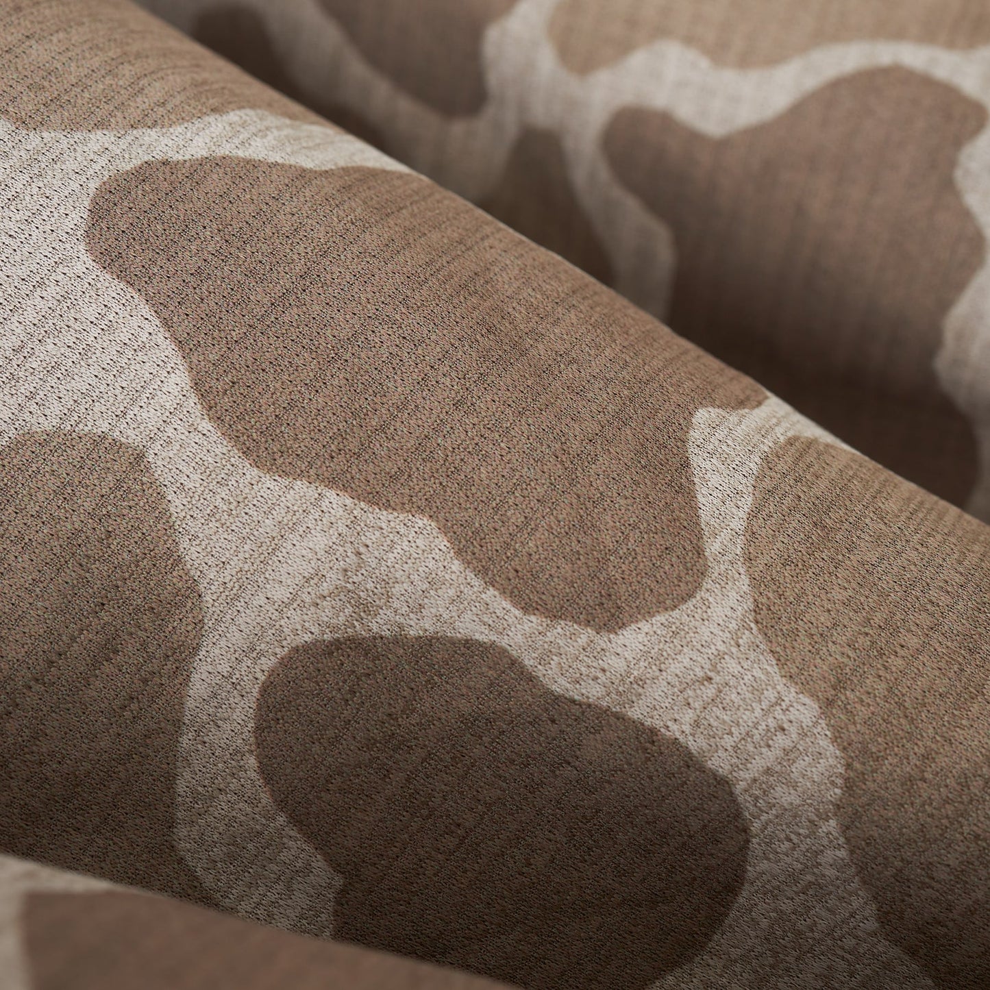 Close-up of textured, taupe long-sleeve shirt with an abstract pattern.
