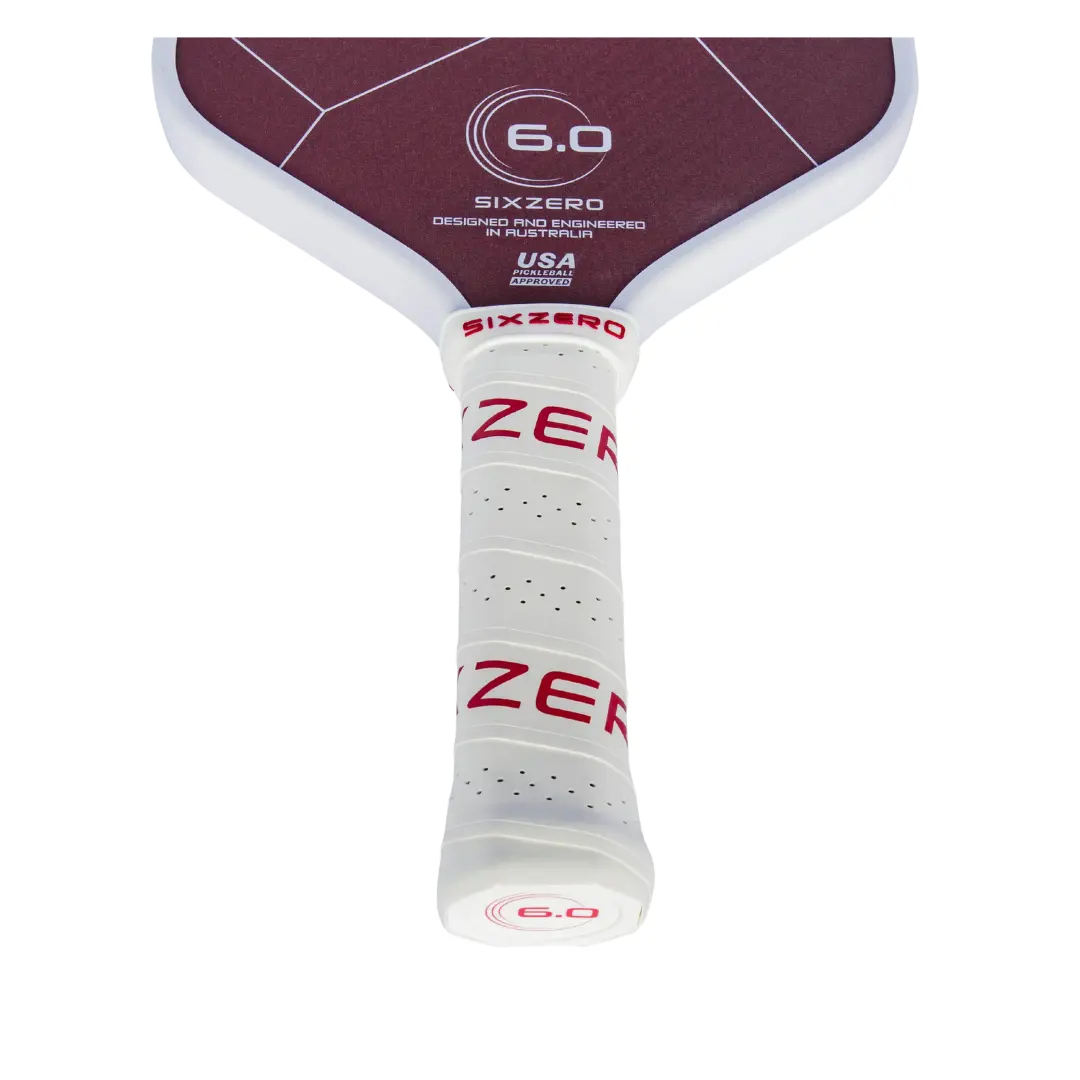 Close-up of a pickleball paddle's grip, showcasing its white perforated design and maroon accents.
