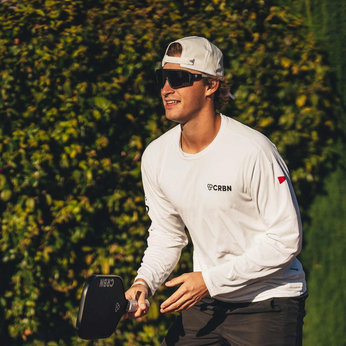 Pickleball player wearing wraparound sunglasses outdoors.
