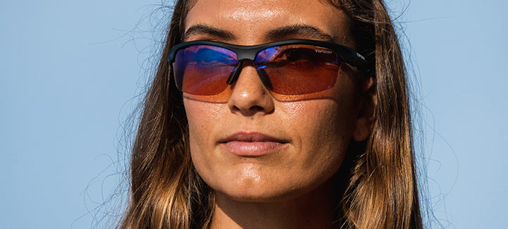 Woman outdoors wearing matte black sunglasses with amber-tinted lenses.
