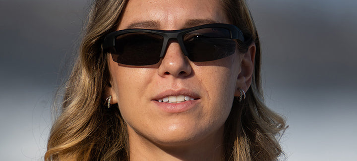 Woman wearing dark sunglasses outdoors.
