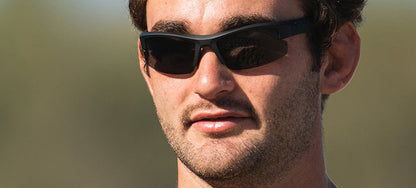 Man wearing dark, sporty sunglasses outdoors.
