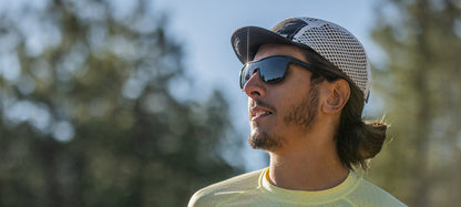 Man in a cap and sunglasses outdoors, enjoying the sunny weather.
