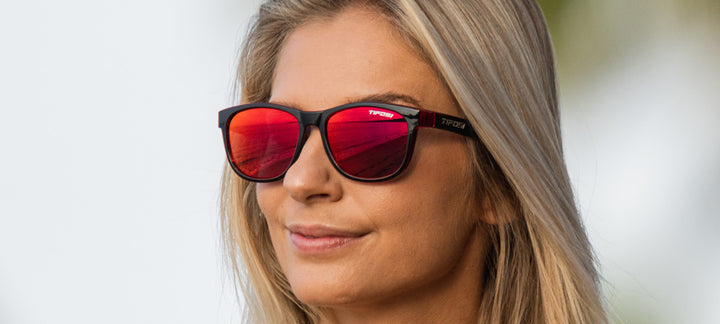 Woman wearing stylish red mirror sunglasses outdoors.
