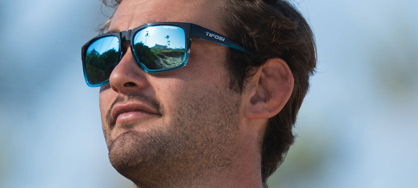 Man wearing blue mirrored sunglasses outdoors.
